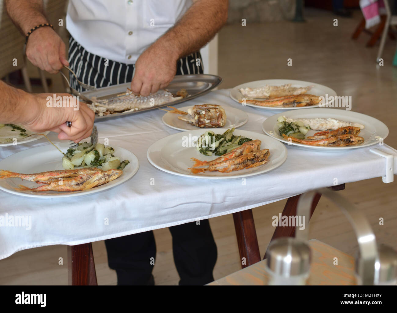 I cuochi servono freschi pesce di mare in un ristorante di pesce Foto Stock