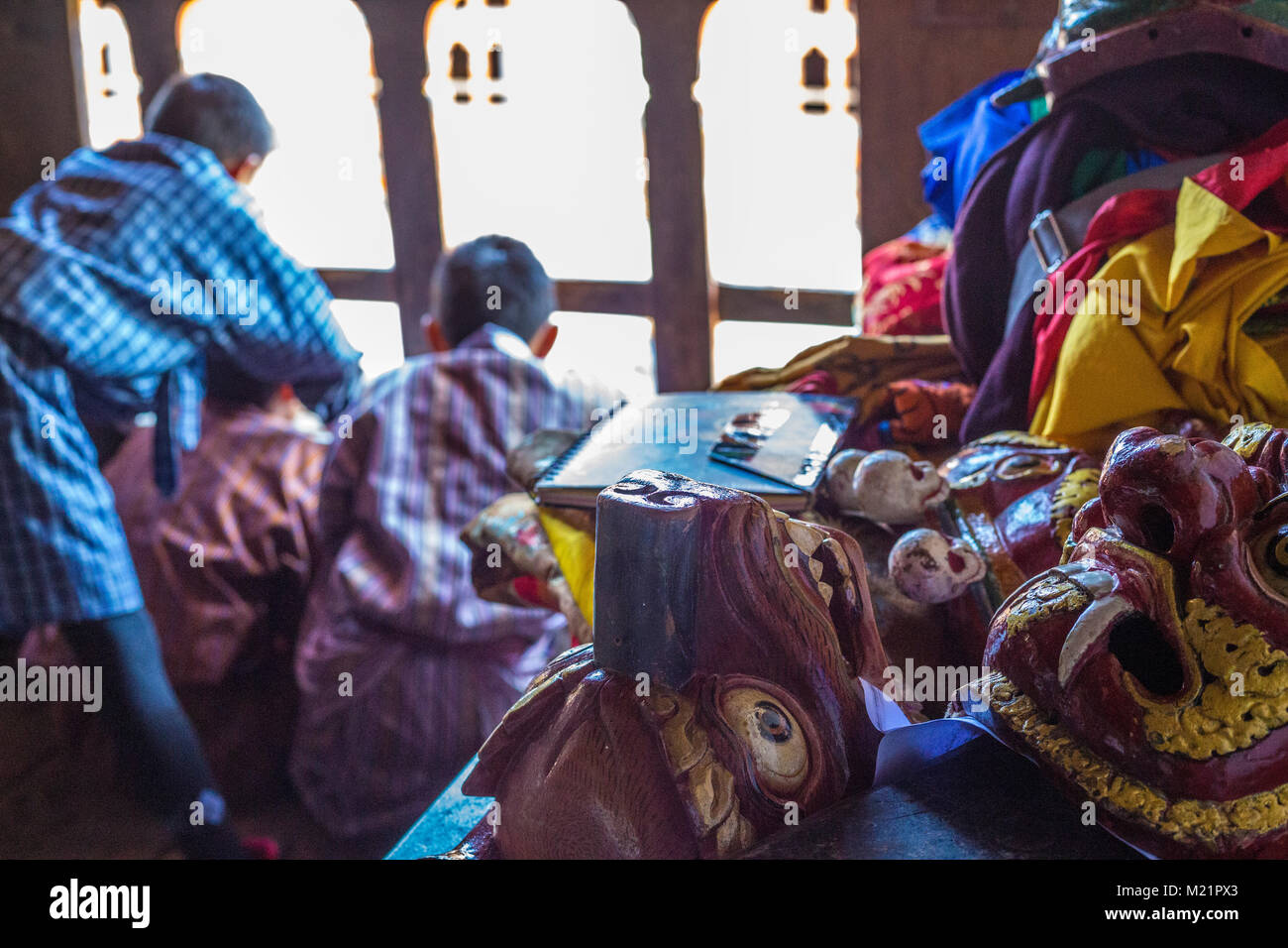 Prakhar Lhakhang, Bumthang, Bhutan. Maschere di danza Waiiting fino alle necessarie mentre i ragazzi guardare ballare sotto, Foto Stock