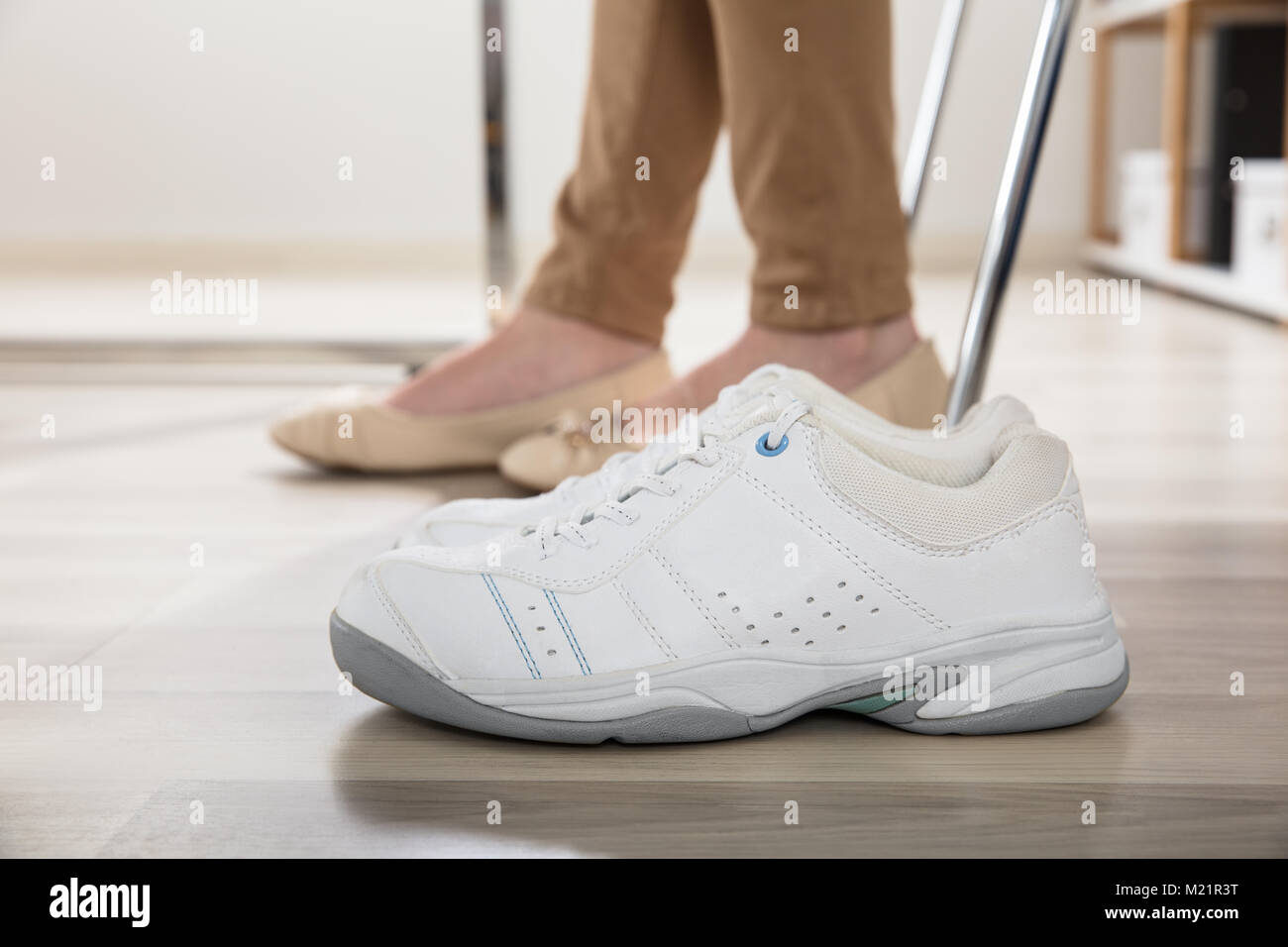 Coppia di un bianco di scarpe sportive oltre a imprenditrice per le gambe in Office Foto Stock