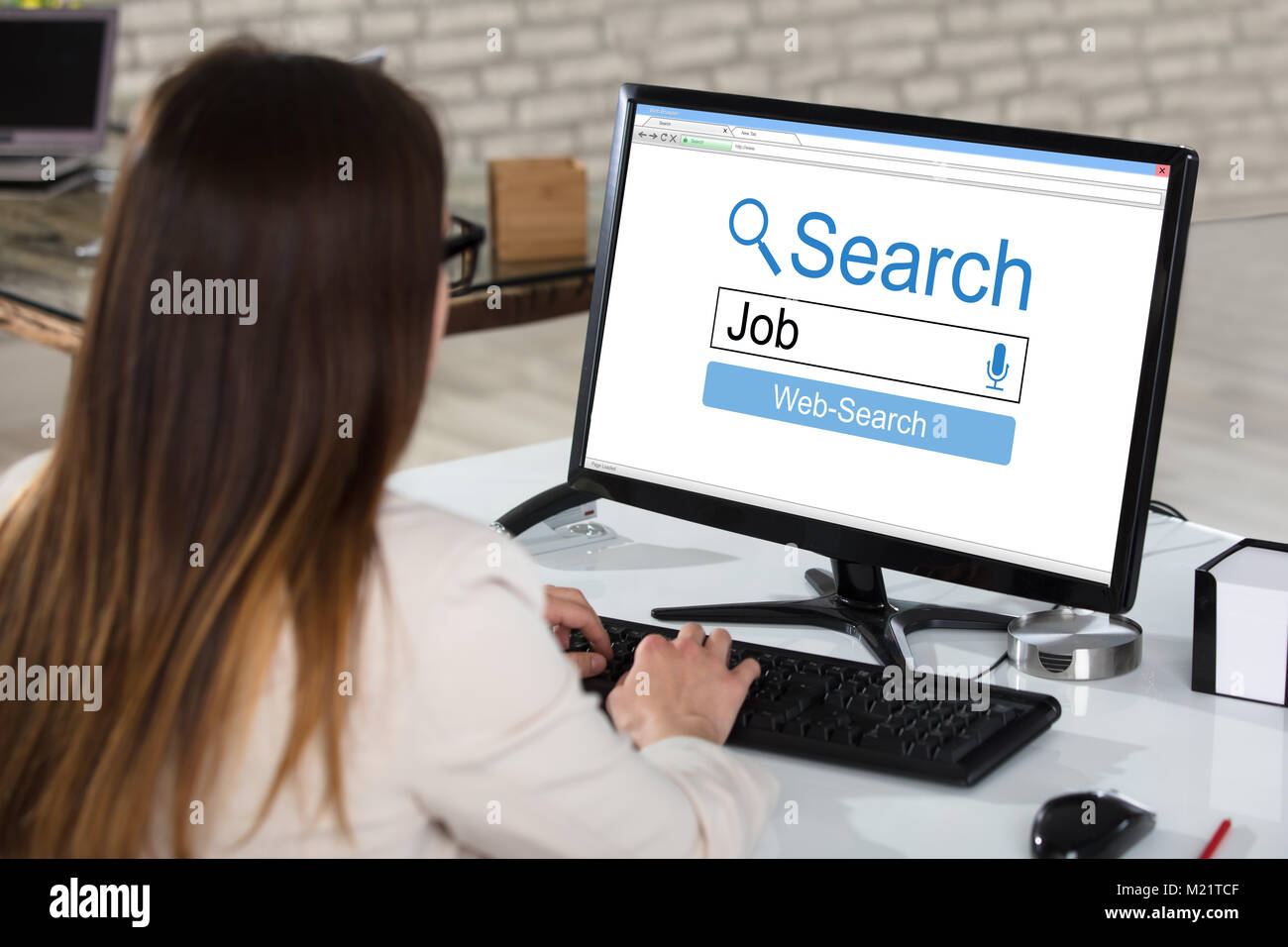 Vista posteriore di una imprenditrice la ricerca di lavoro online sul computer in ufficio Foto Stock