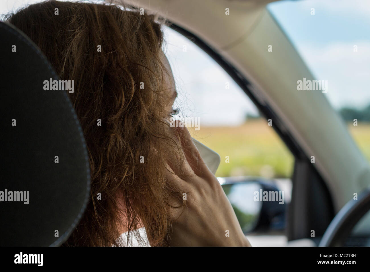 Una giovane donna aziona una vettura e parla al telefono ed è distratto Foto Stock
