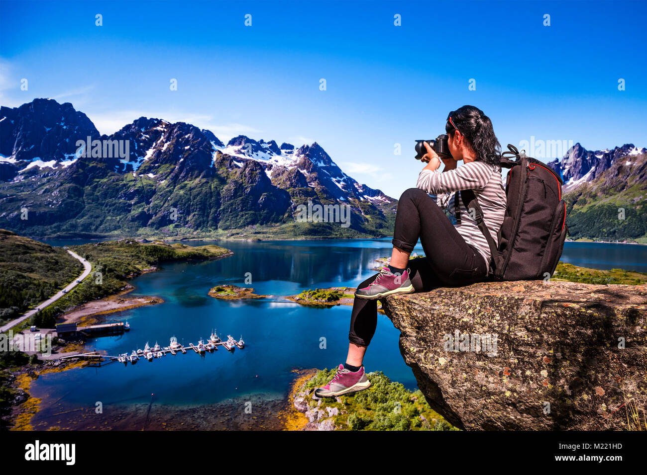 Fotografo di natura turistico con fotocamera germogli mentre permanente sulla cima della montagna. La bellissima natura della Norvegia Lofoten arcipelago. Foto Stock