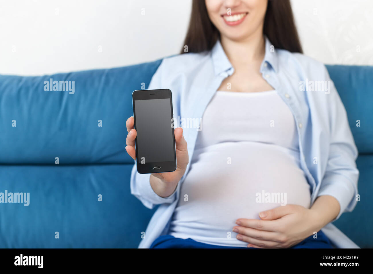 Donna incinta tenendo il telefono con display vuoto Foto Stock