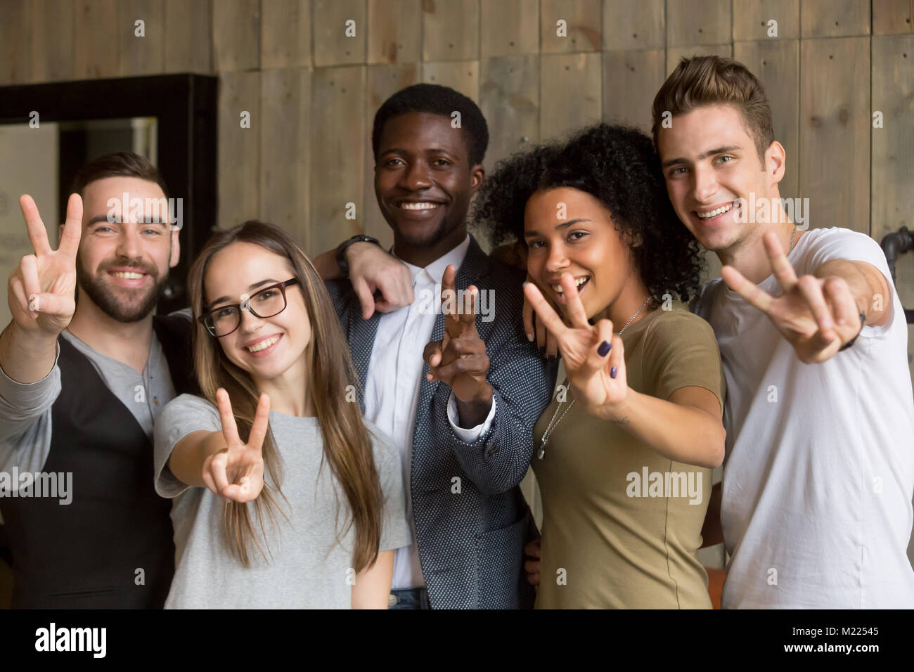 Felice multi-etnico giovani che mostrano segni di pace guardando ca Foto Stock