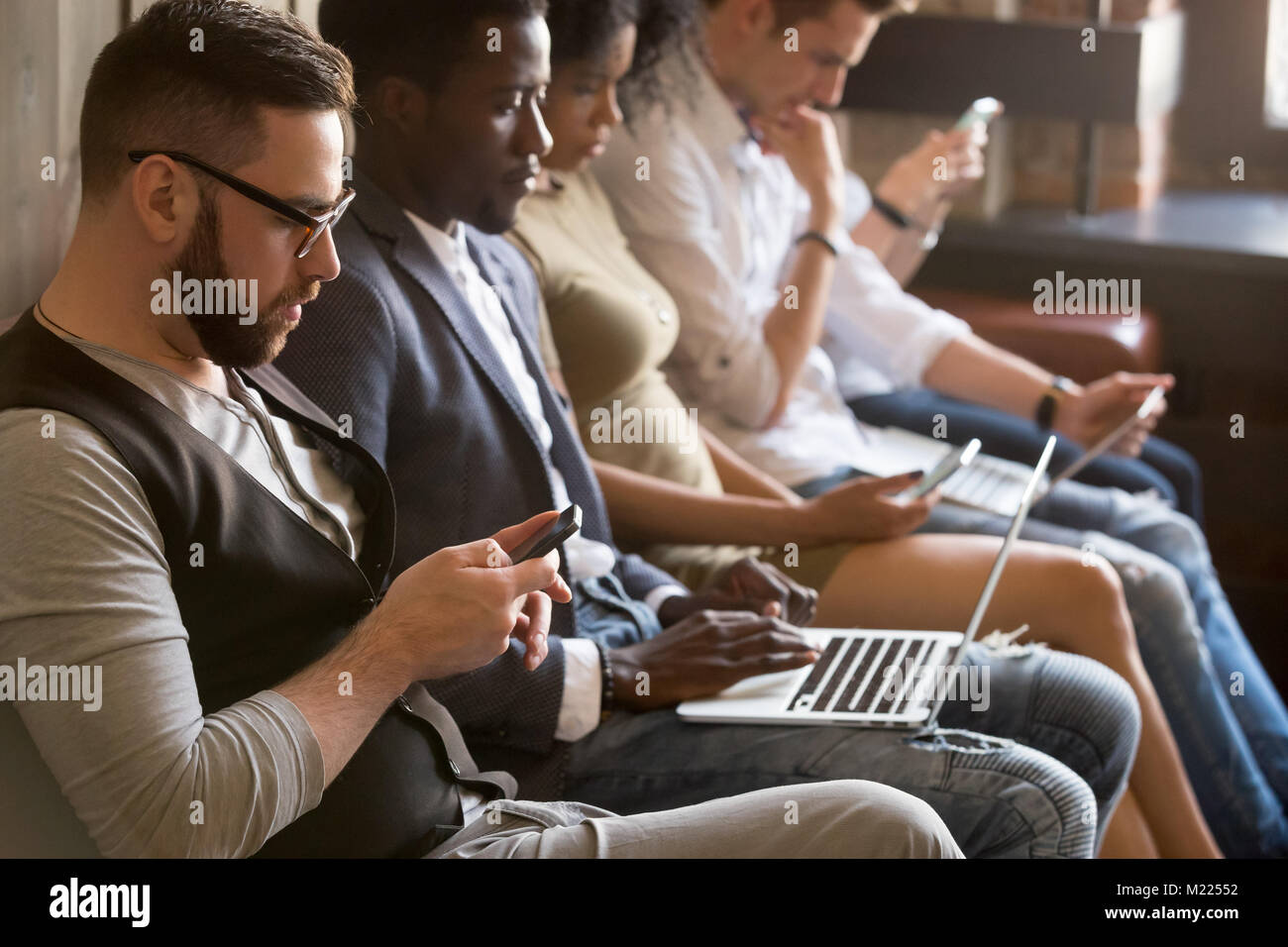Multi etnico gruppo di giovani usando dispositivi elettronici indo Foto Stock