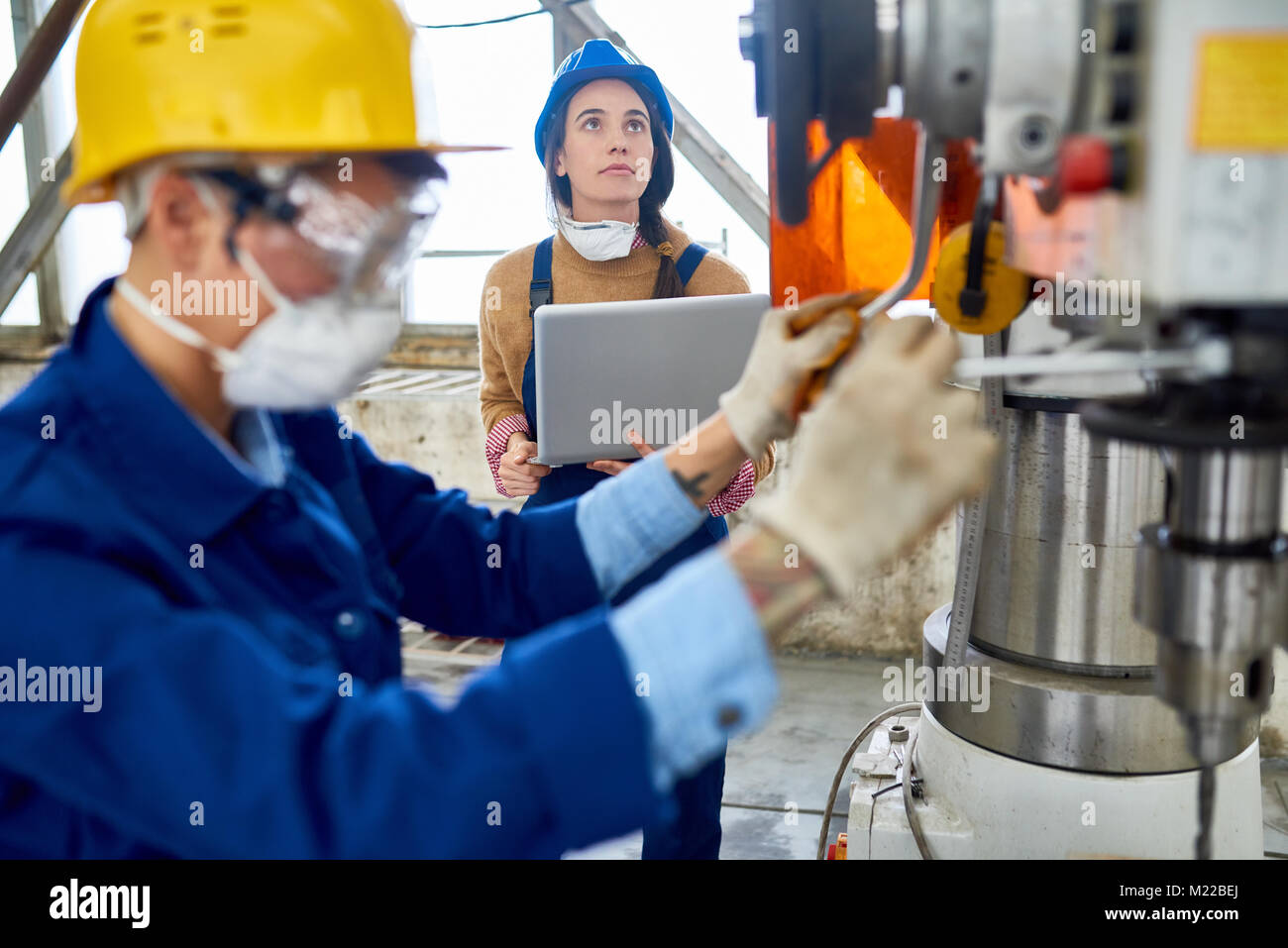 Vista laterale Ritratto di giovane donna indossa hardhat e uniforme di macchina operatrice unità a impianto moderno spazio di copia Foto Stock