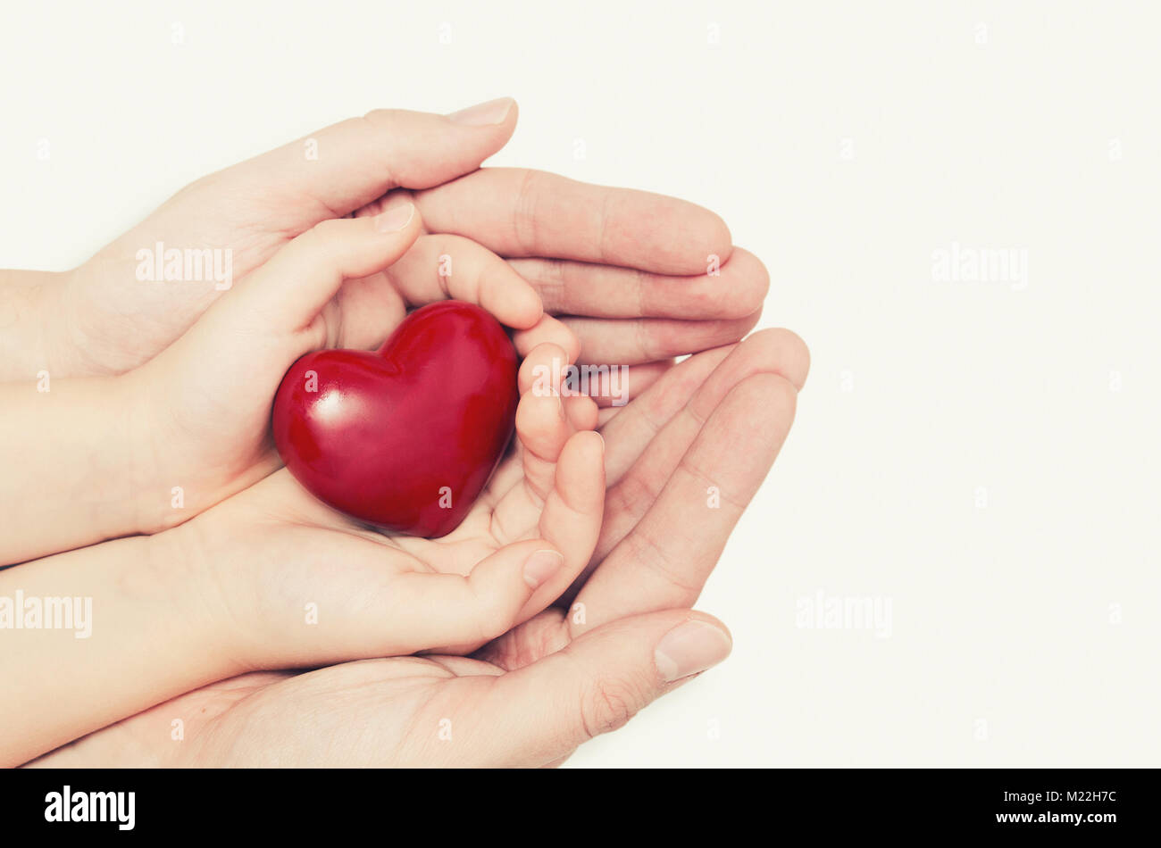 Genitore e bambino tenendo il cuore in mano. La cura della salute, famiglia il concetto di assicurazione Foto Stock