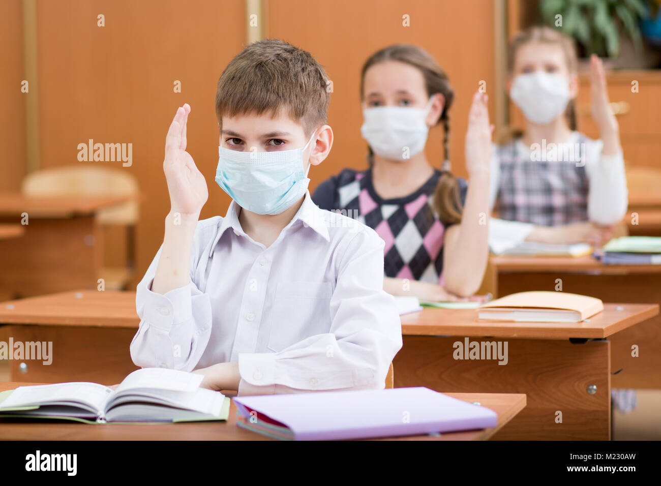 Schoolkids con maschera di protezione contro virus influenzale a lezione in aula Foto Stock
