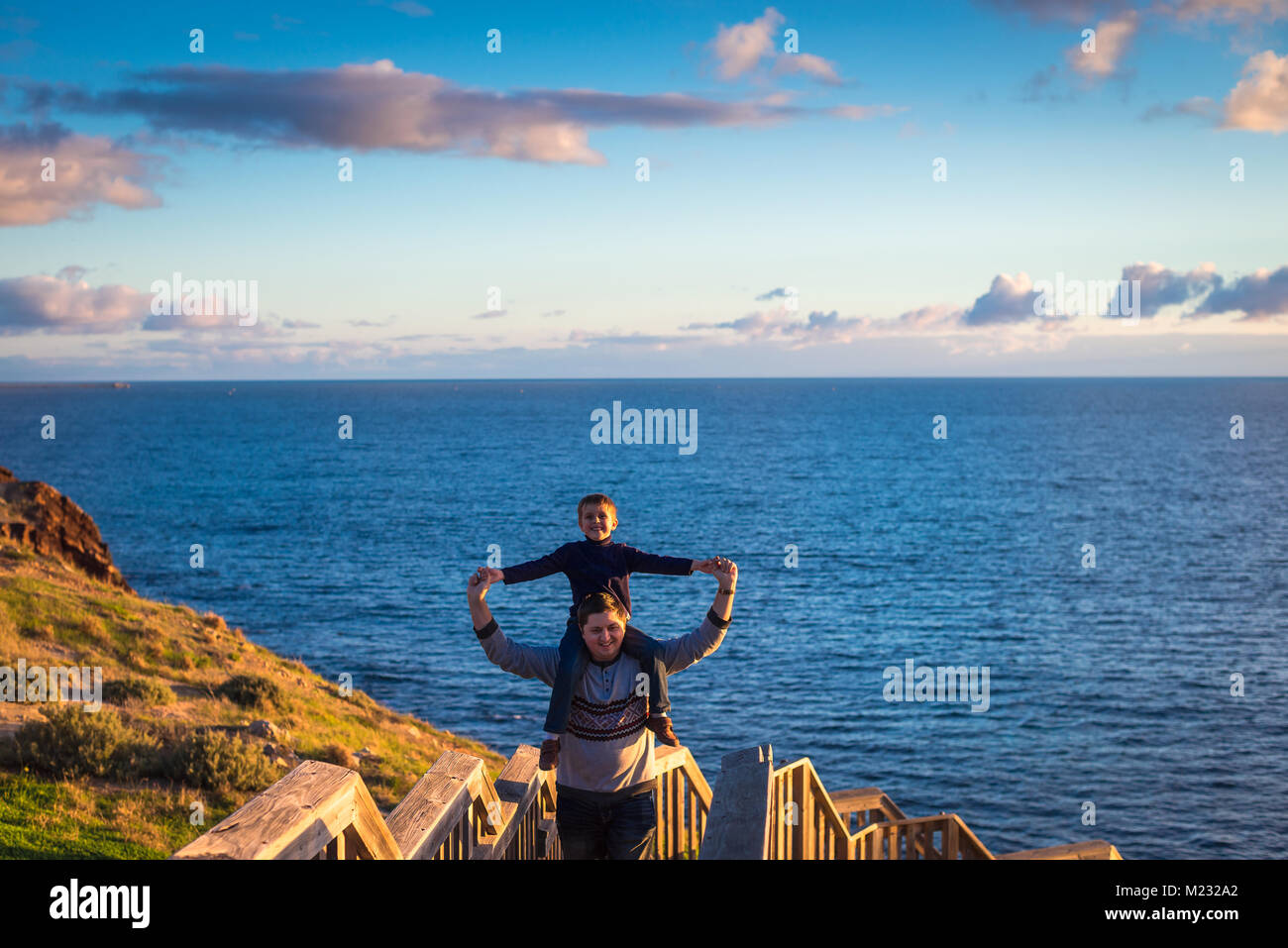 Padre dando il suo figlio piggyback ride a Hallett Cove boarwalk mentre godendo del tramonto, Sud Australia Foto Stock