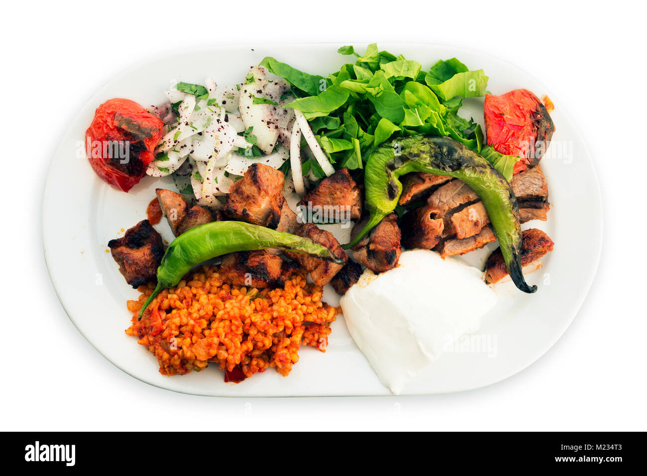 Piatto di spiedini di carne di agnello con cipolla riso rosso, pomodori arrostiti e pepe su uno sfondo bianco. Foto Stock