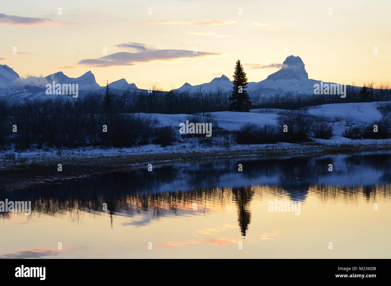 Una stupenda scena invernale con Chief mountain riflette il lago al tramonto Foto Stock