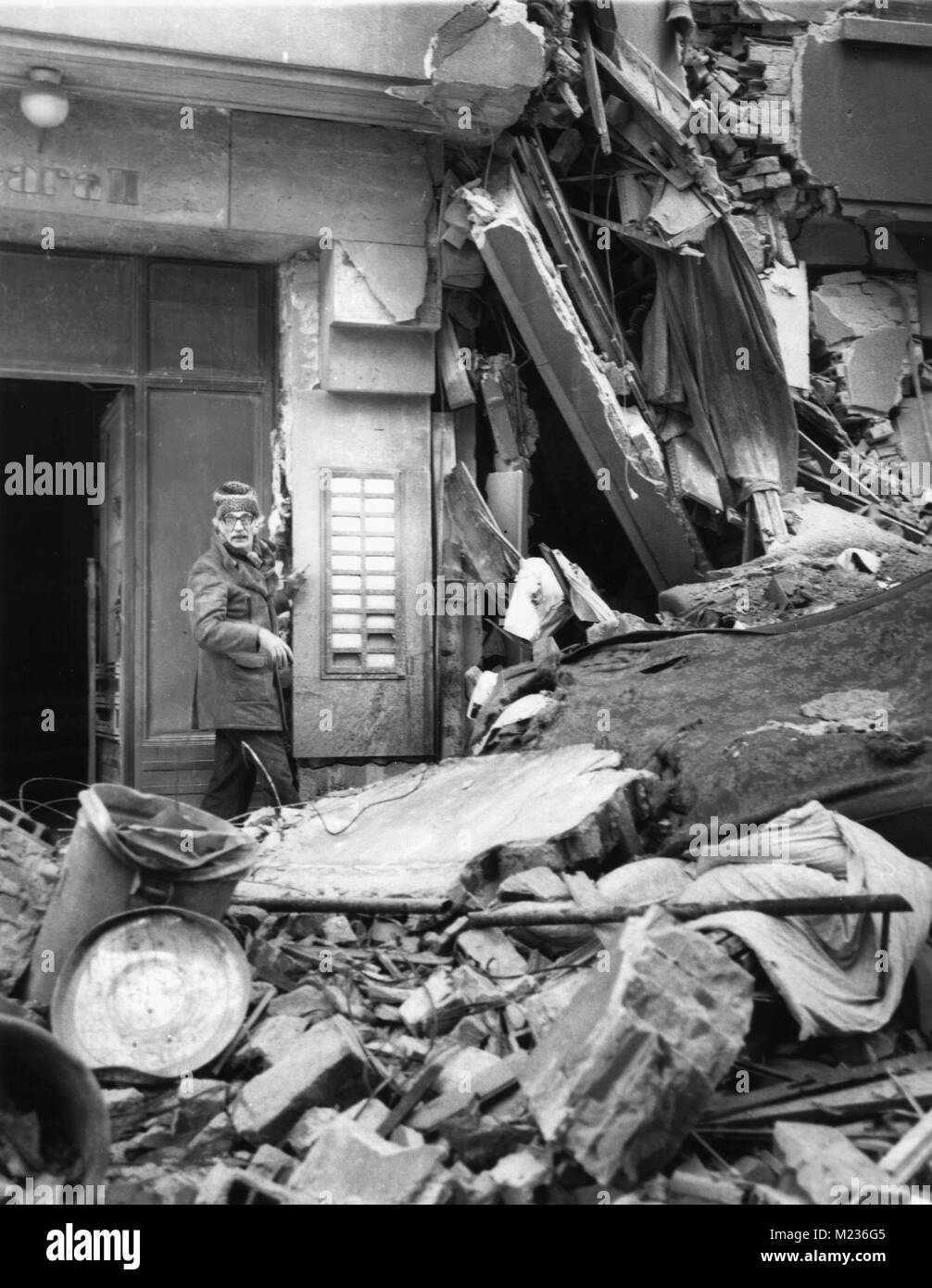 Il vecchio uomo a camminare tra le macerie di appartamento edificio distrutto dal terremoto del mese di marzo 1977 a Bucarest, Romania Foto Stock