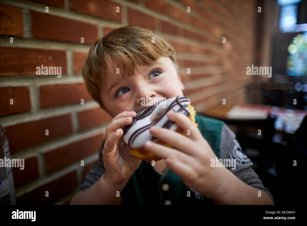 New York City Manhattan, Ottava Avenue boy mangiando grandi ciambella torta Foto Stock