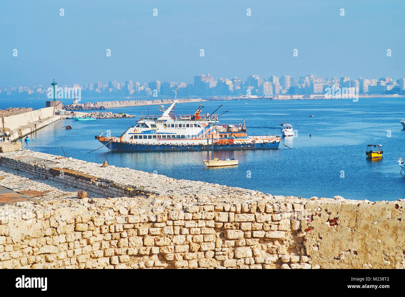 Il fumoso porto orientale con un lungo molo vecchio, la pesca a strascico costiera e quartieri residenziali sullo sfondo, Alessandria, Egitto. Foto Stock
