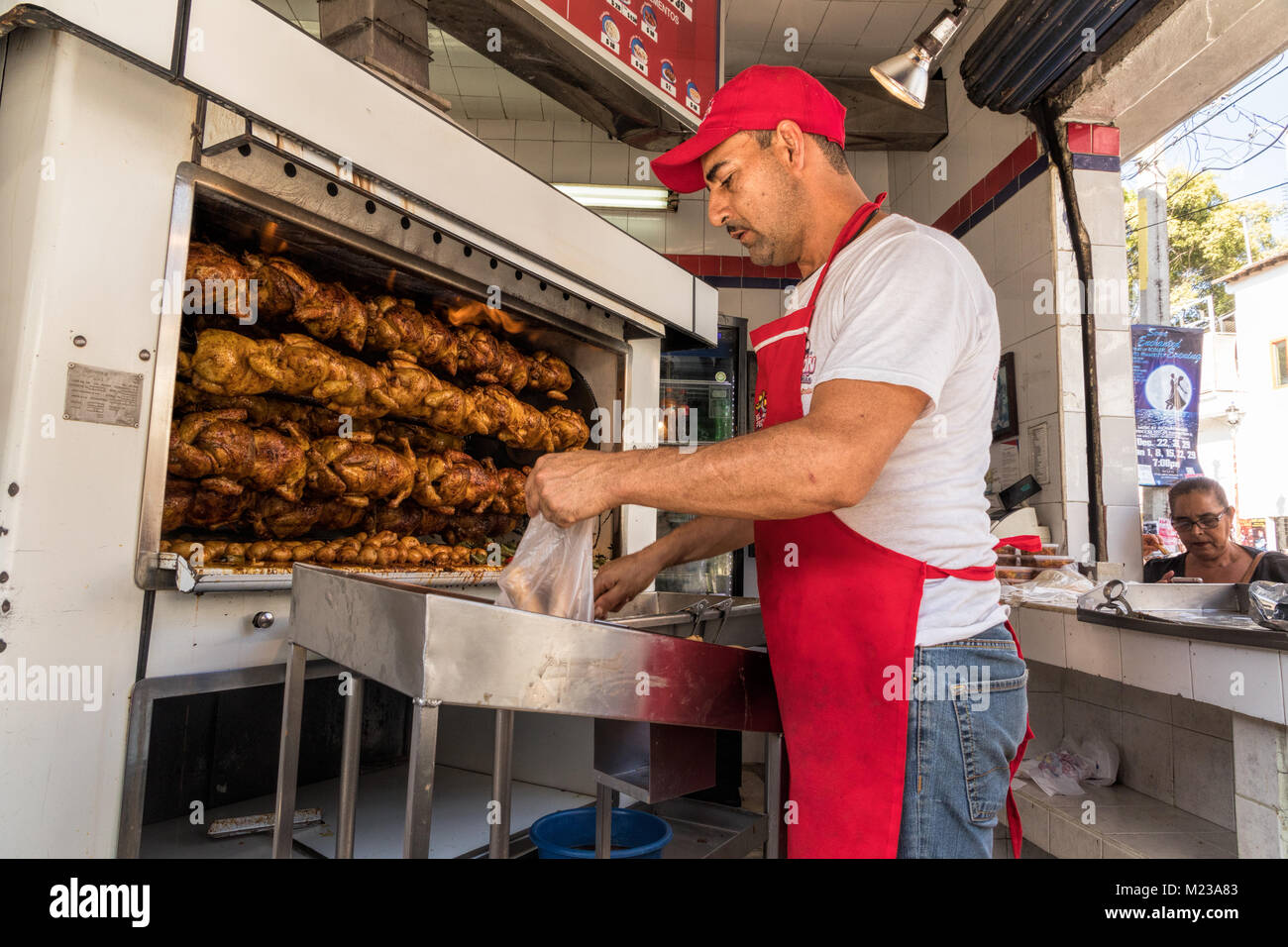 Uomo che serve pollo caldo sulla strada a Puerto Vallarta, Messico. Foto Stock