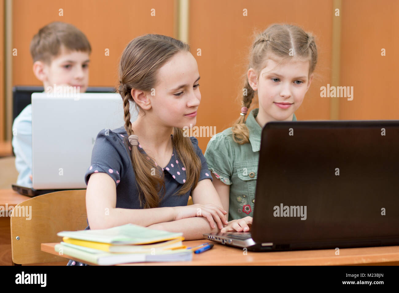 Scuola felice i ragazzi al computer portatile in aula Foto Stock