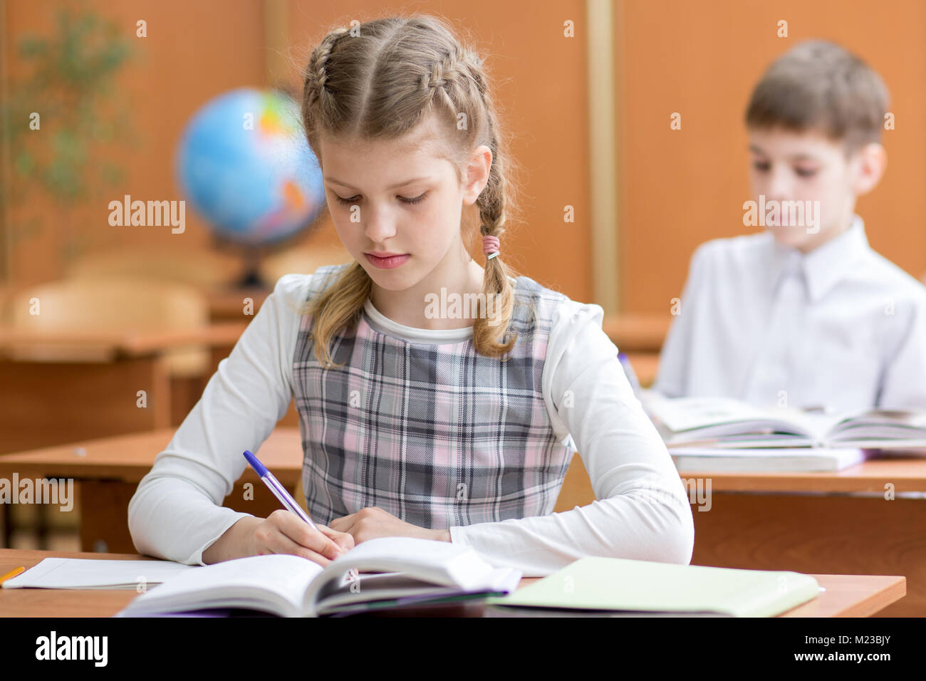 Ragazza di scuola di scrittura in notebook a lezione in aula Foto Stock