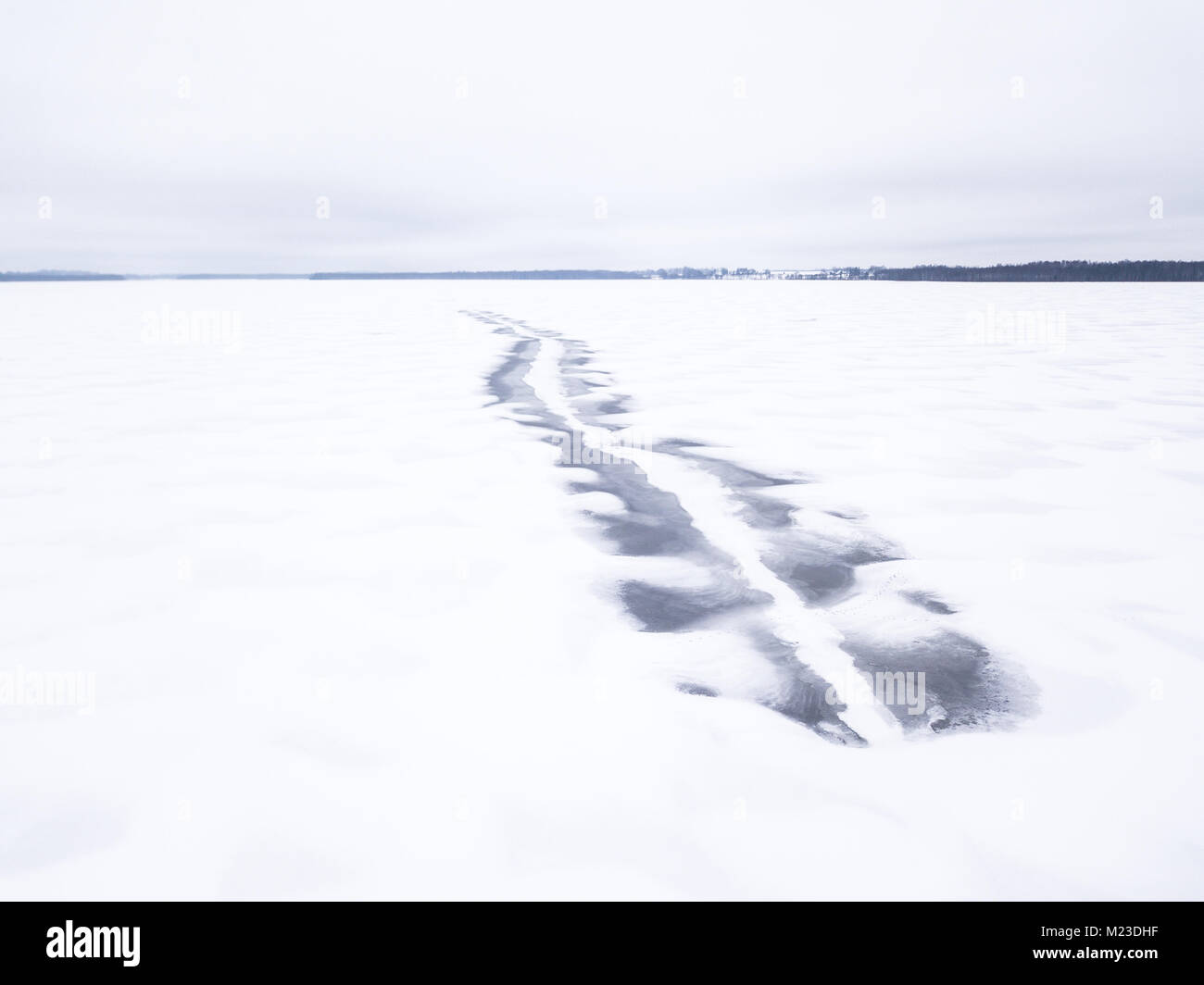 Fuso motoslitta scuro tracce su una congelati coperta di neve sul lago. Tartu, Estonia. Foto Stock