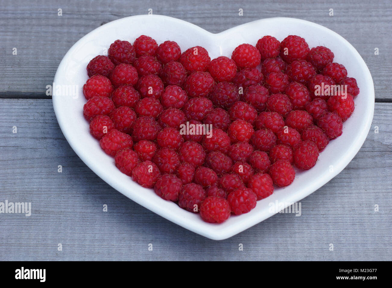Cuore rosso fatta di lampone. Fresche, succosa e fragrante di frutti di bosco Lamponi sono posati su un piatto. Foto Stock