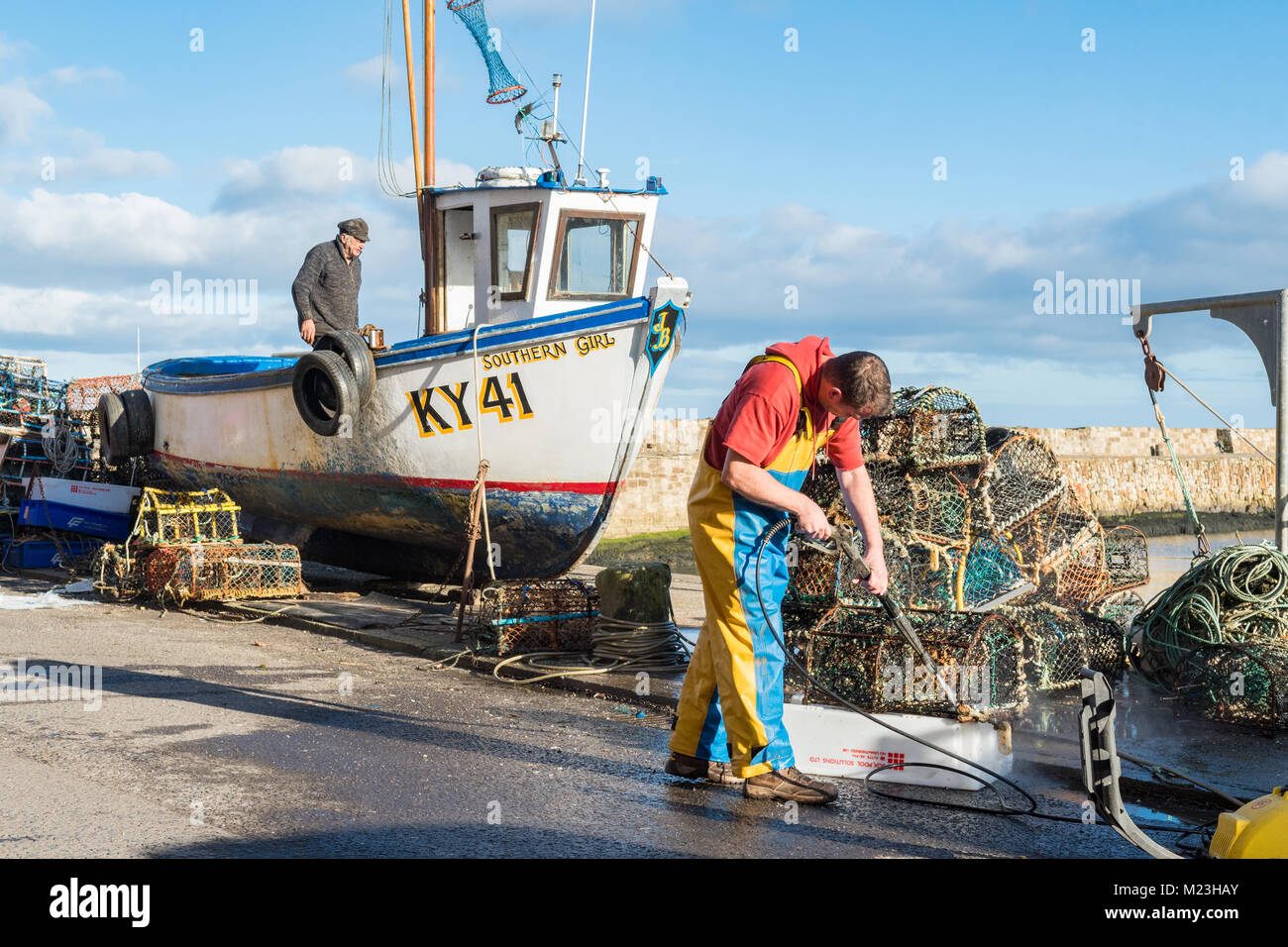 Fisherman pulizia pentole di aragosta e potter piccola barca da pesca a St Andrews Harbour, St Andrews, Scotland, Regno Unito Foto Stock