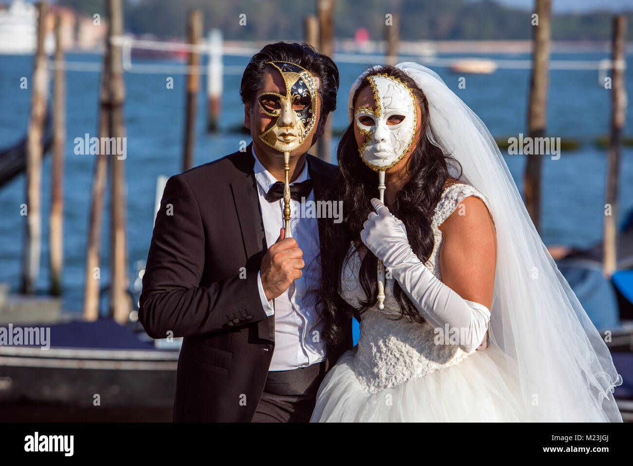 Coppia sposata dietro veneziano maschere di nozze, Venezia, Italia Foto Stock