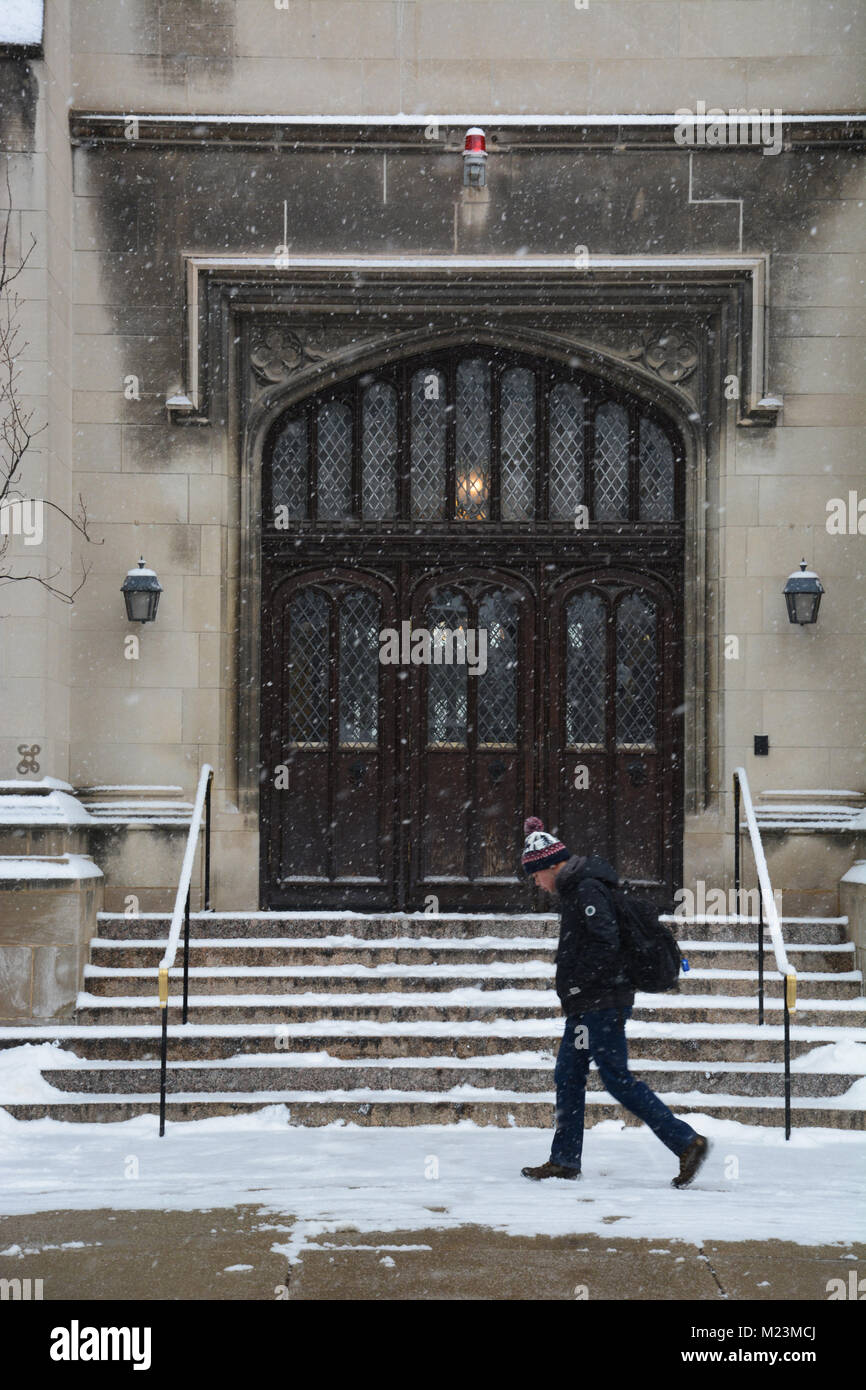 Uno studente di passeggiate nella neve passato porte gotiche di Harper Memorial Library su l'Università di Chicago campus. Foto Stock