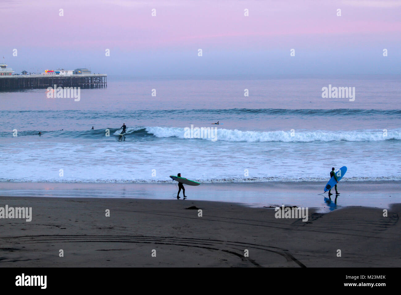 Surfisti sulla Cowell la spiaggia al tramonto, Santa Cruz, in California, negli Stati Uniti Foto Stock