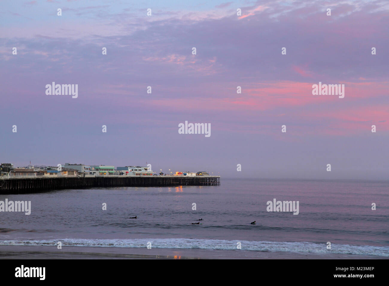 I surfisti al tramonto su Cowell's Beach, Santa Cruz Wharf in background, Santa Cruz, in California, negli Stati Uniti Foto Stock