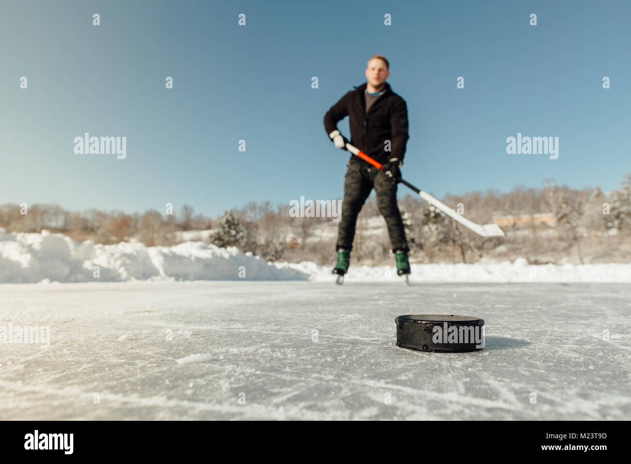 L'uomo la riproduzione di hockey su ghiaccio su un lago ghiacciato di focalizzazione su un puck Foto Stock