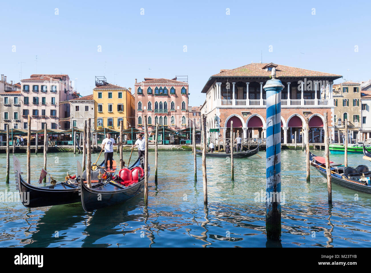 Due gondolieri il recupero dei loro gondole di fronte al Ponte di Rialto Mercato del Pesce sul Canal Grande, San Polo, Venezia, Veneto, Italia a inizio giornata in sp Foto Stock