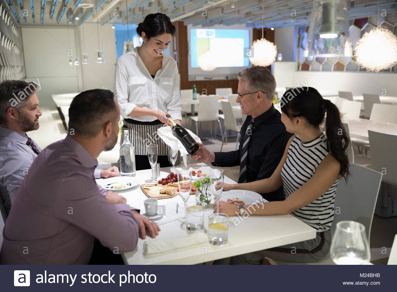 Cameriera presentando una bottiglia di champagne per la gente di affari presso il ristorante la tabella Foto Stock
