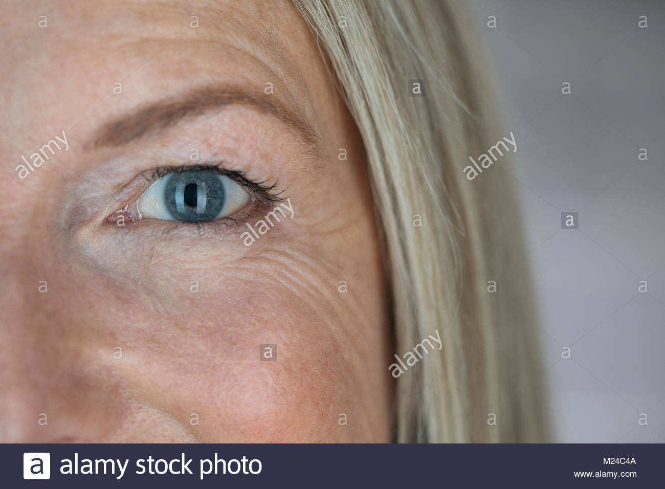 Close up fiducioso donna matura con gli occhi blu e linee di sorriso Foto Stock