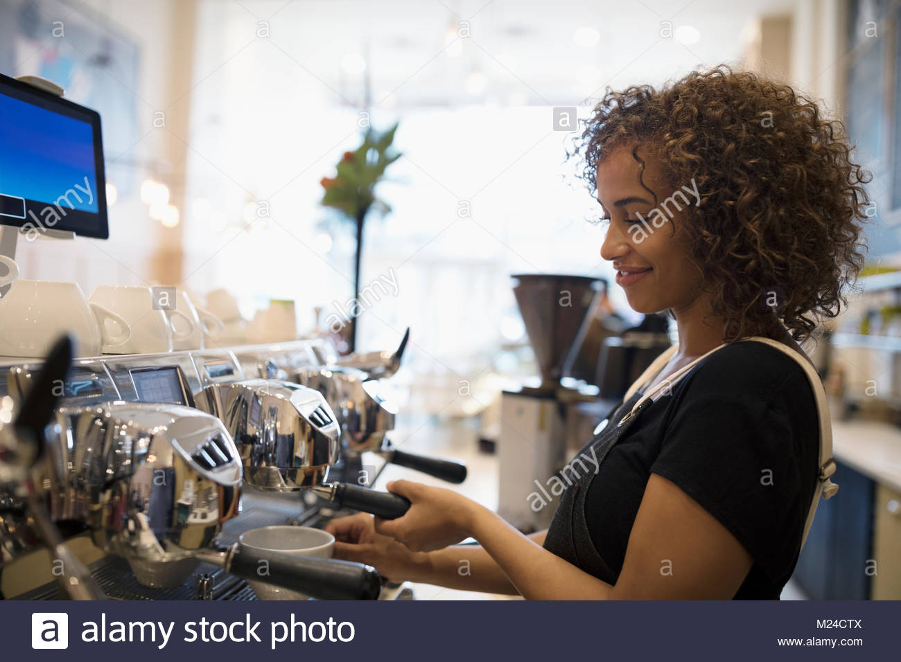 Donna sorridente barista preparare il caffè a macchina espresso in cafe Foto Stock