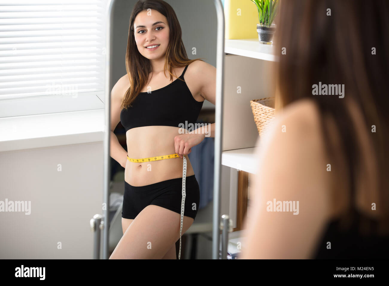 Close-up di una donna di riflessione dello specchio misurando il suo ventre Foto Stock