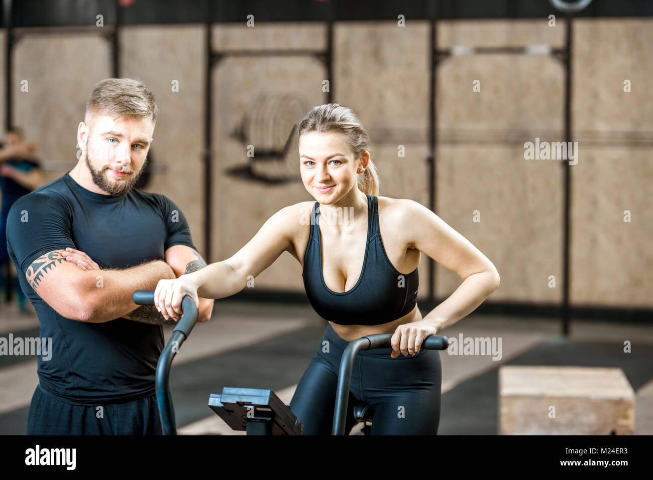 Donna formazione sulla cyclette con trainer in palestra Foto Stock