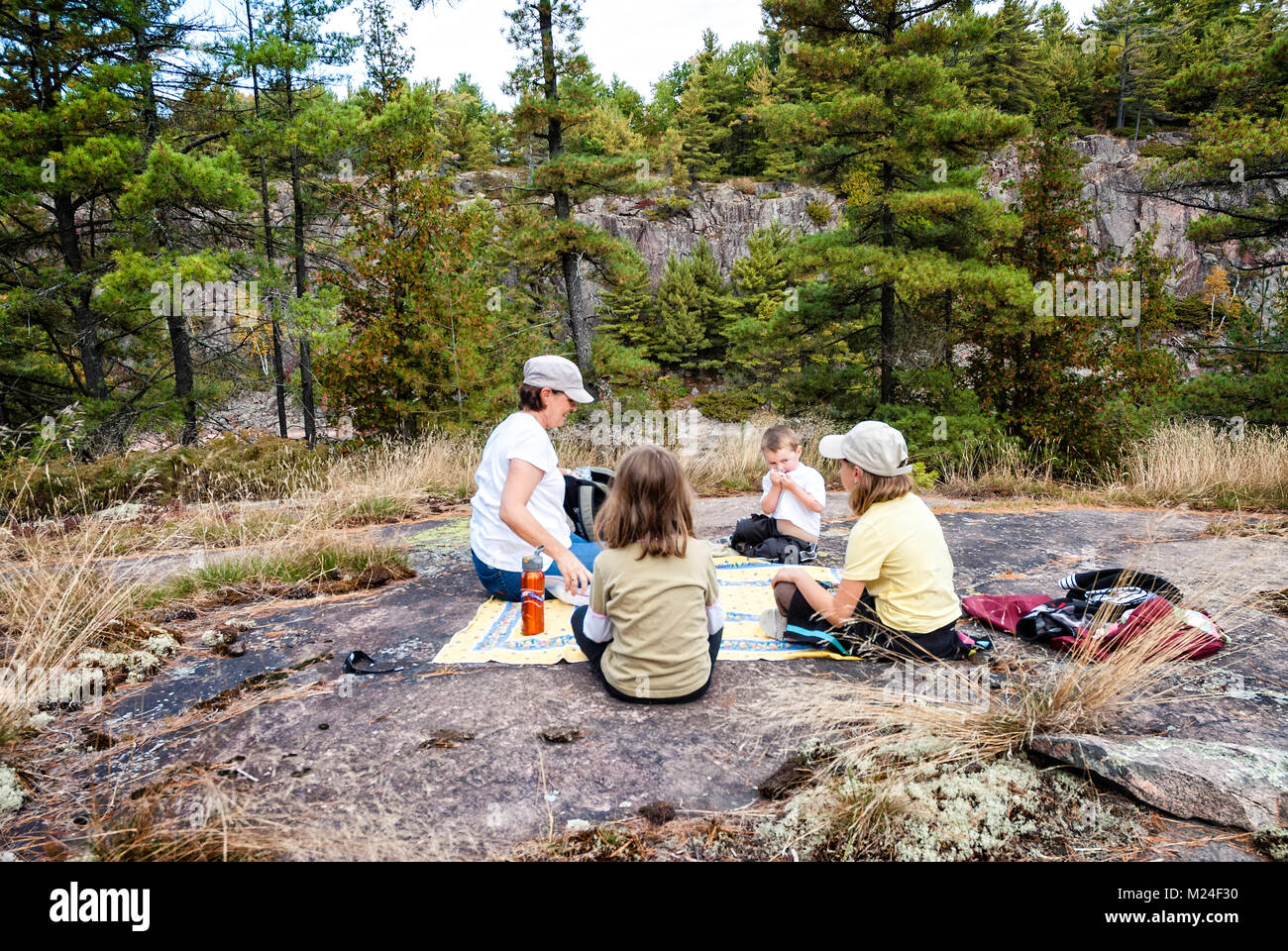Una nonna e nipoti hanno un picnic su una roccia nel nord Ontario Foto Stock