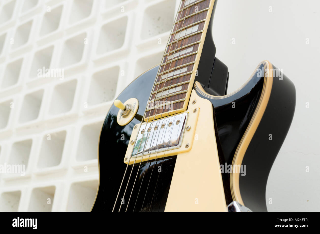 Nero chitarra elettrica su uno sfondo bianco parte bianca e la parte piena di fori Foto Stock