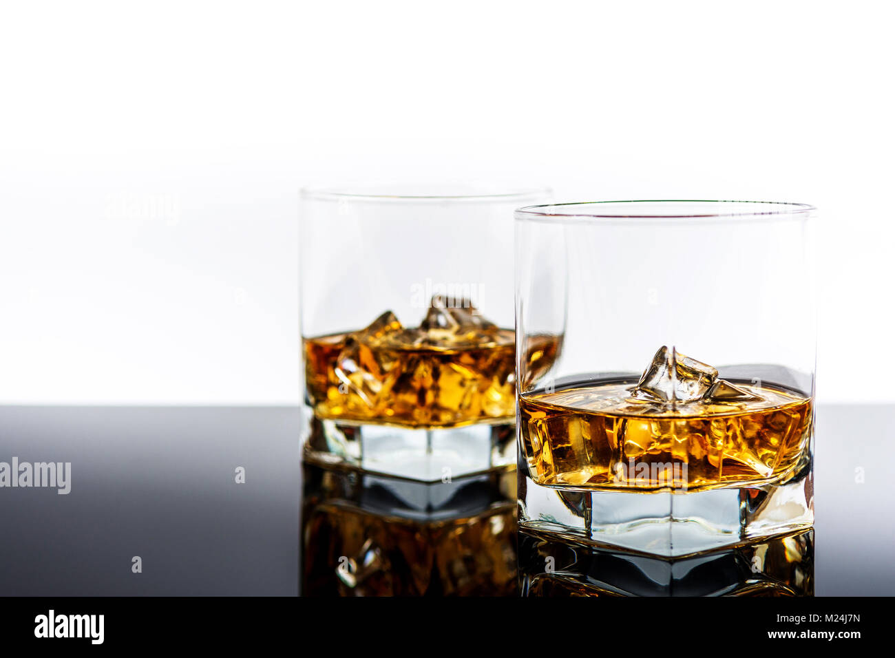 Whisky e whiskey Bourbon o con ghiaccio sul retro la riflessione sullo sfondo Foto Stock