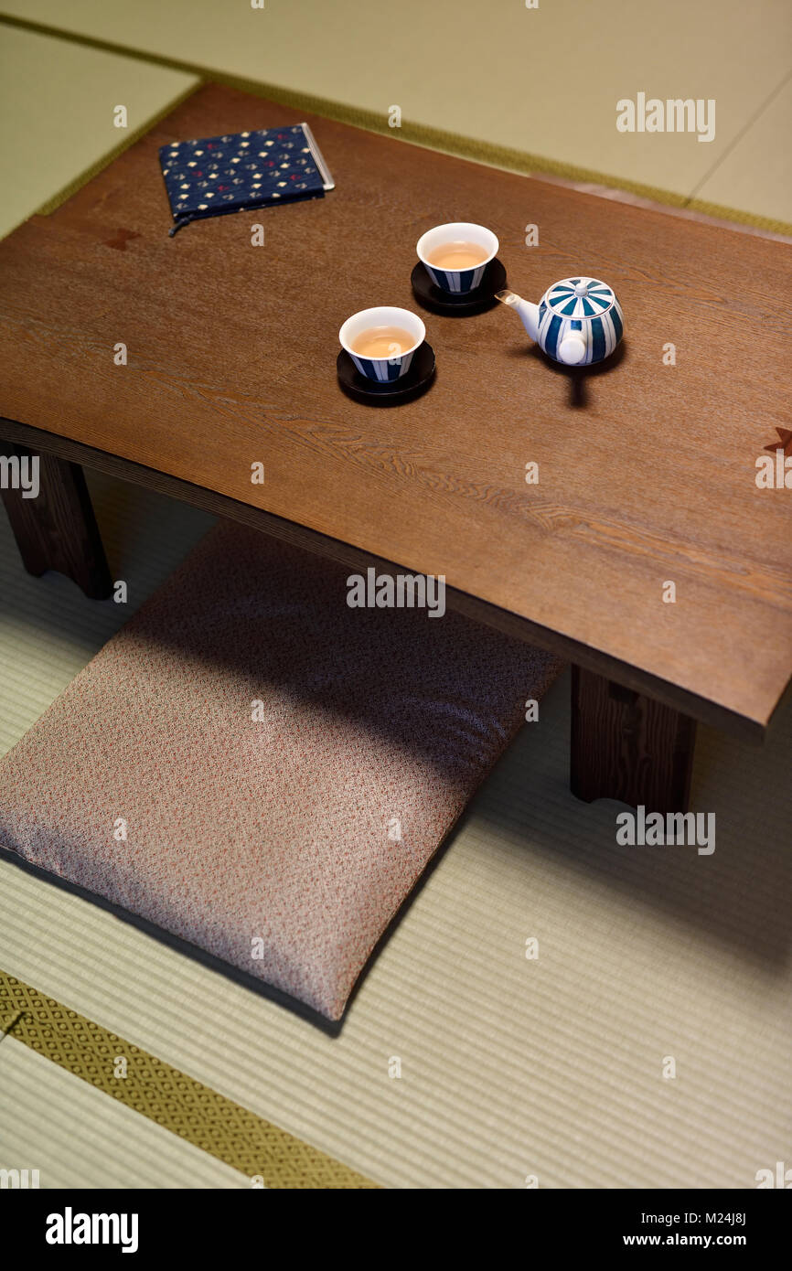 Breve giapponese-gambe di legno tavolo da tè, Chabudai, con una teiera e due tazze, seduta cuscini zabuton sul Tatami di una tradizionale camera giapponese Foto Stock