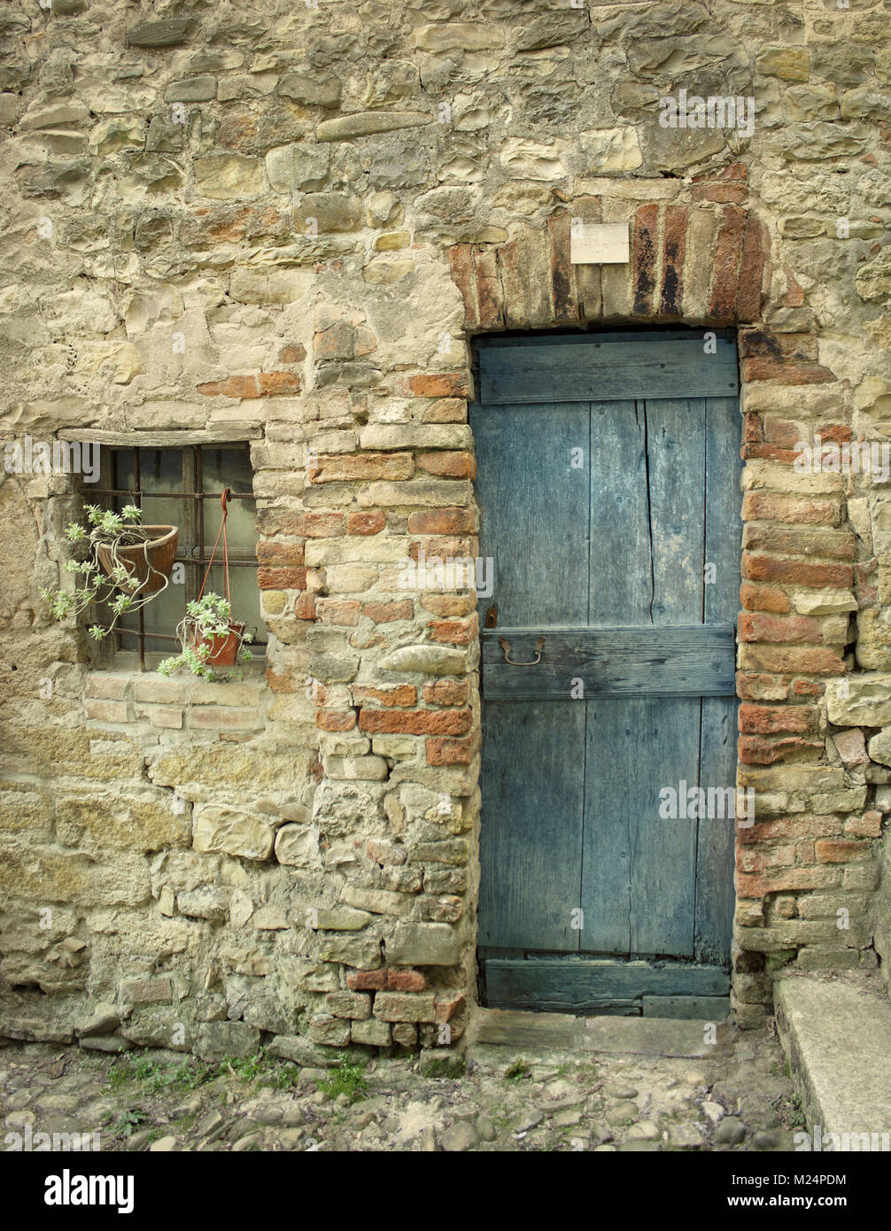 Dettaglio di una vecchia facciata con porta e una piccola finestra di casa colonica Foto Stock