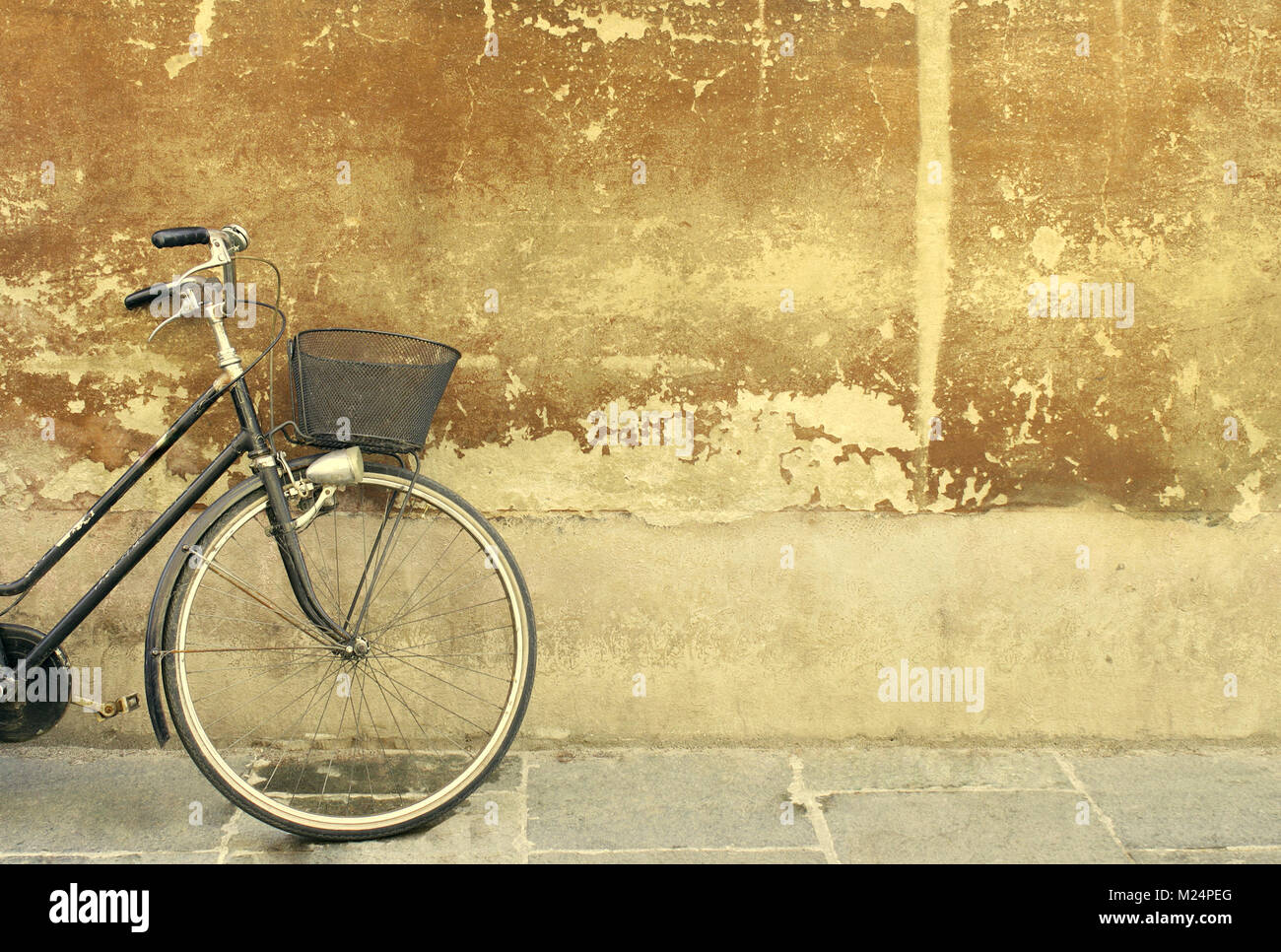 Particolare di una parte di una bicicletta appoggiata contro un vecchio muro Foto Stock