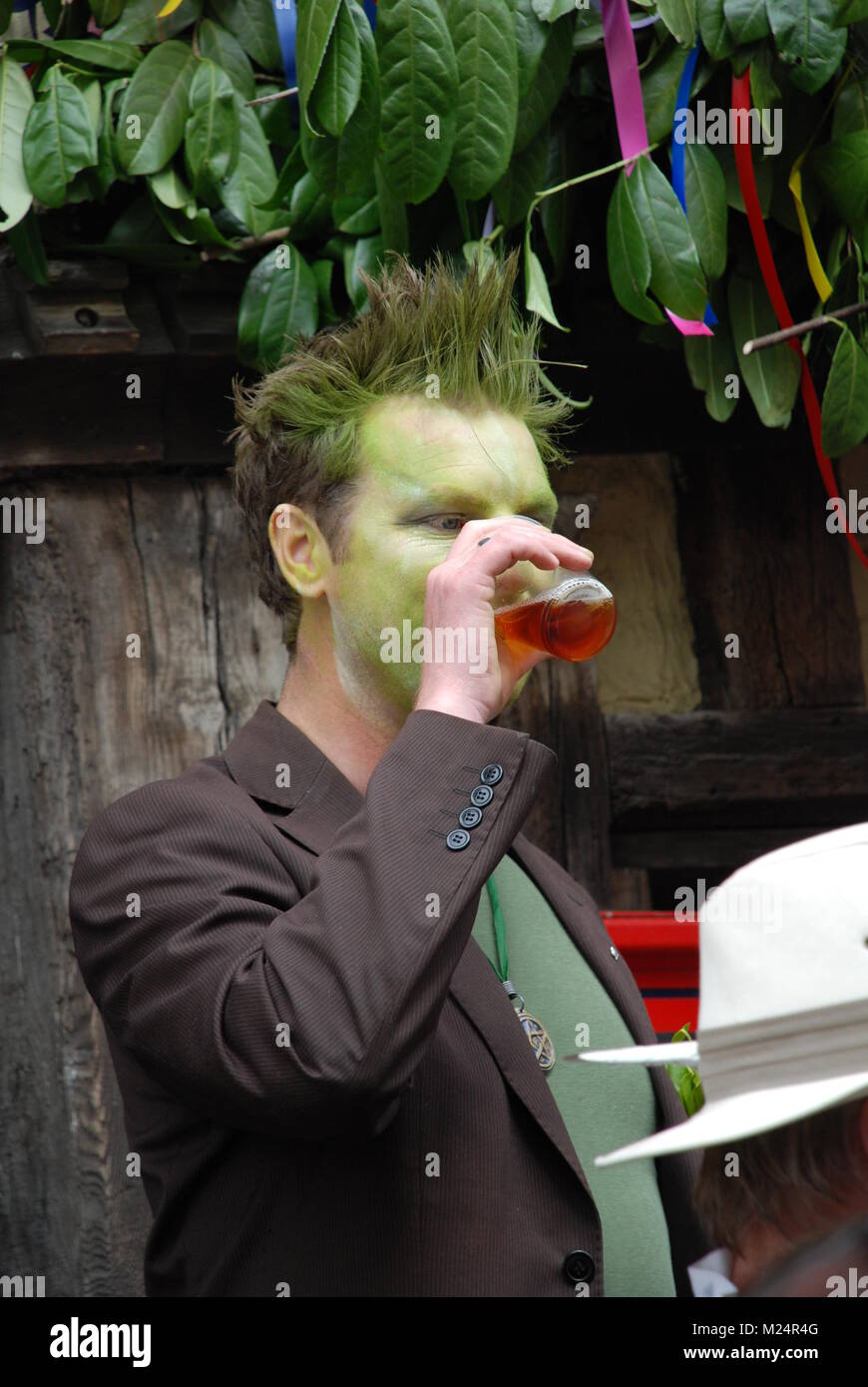 Un festival maschio goer con verde volto tinto beve una birra al Jack nel festival verdi a Hastings in East Sussex, in Inghilterra il 5 maggio 2009. Foto Stock