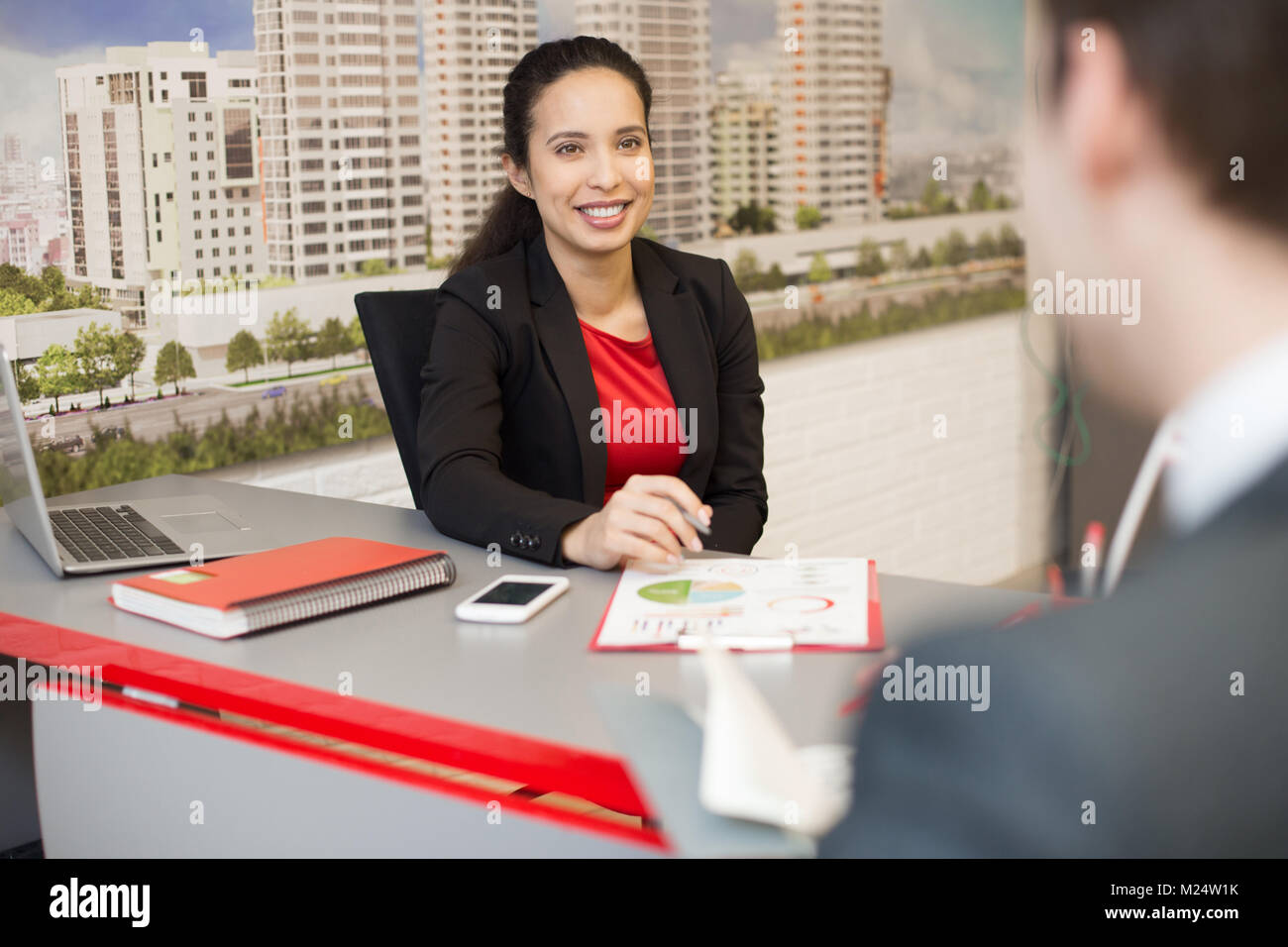 Ritratto di donna agente immobiliare seduto alla scrivania e parlare al cliente sorridendo felicemente in ufficio di agenzia Foto Stock