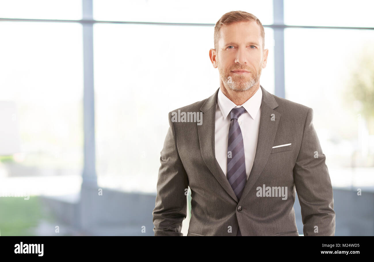 Sorridente executive direttore finanziario imprenditore in piedi presso l'ufficio. Foto Stock