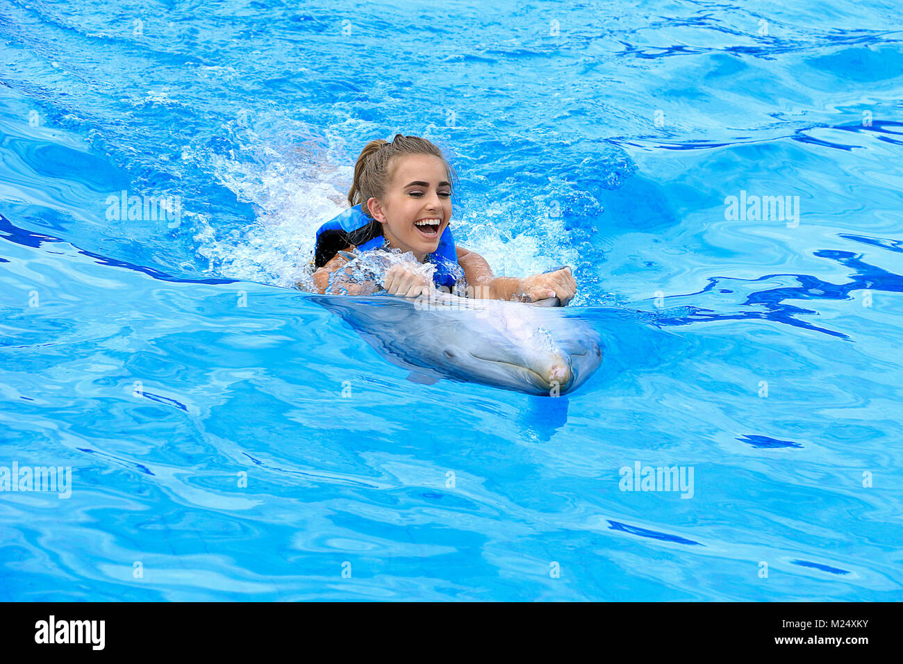 Caucasian ragazza adolescente con delfino in piscina Foto Stock