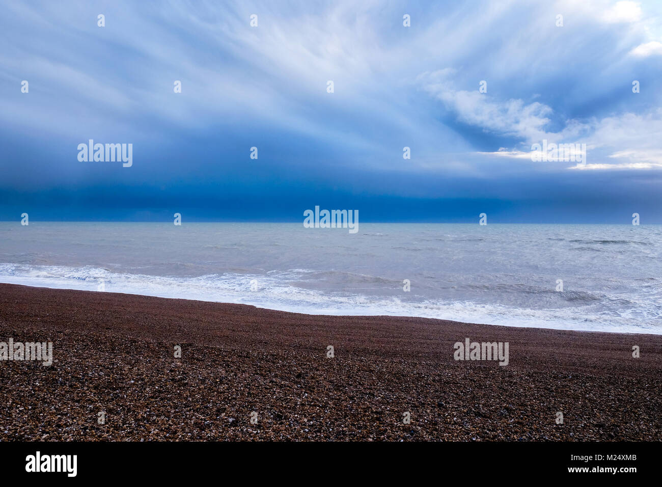 La spiaggia di Brighton, Sussex, Regno Unito, in corrispondenza del fondo una linea di colore rosso sulla spiaggia di ciottoli in mezzo al mare e in cima all'immagine un profondo blu dramati Foto Stock