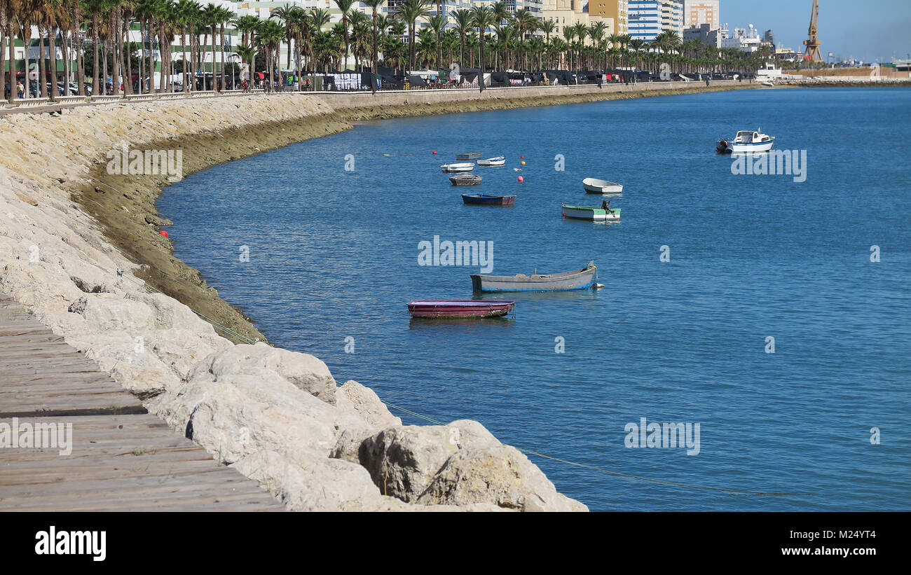 Vista orizzontale della passeggiata sul lungomare e le piccole barche di legno ancorato nel porto di Cadiz, Spagna Foto Stock