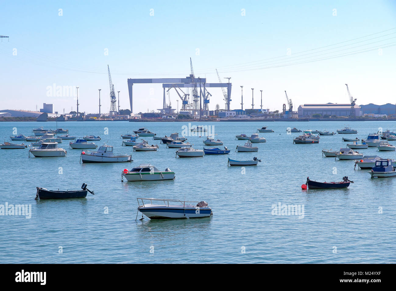 Vista orizzontale di piccole barche di legno ancorato nel porto di Cadiz-Spagna con i cantieri in background Foto Stock