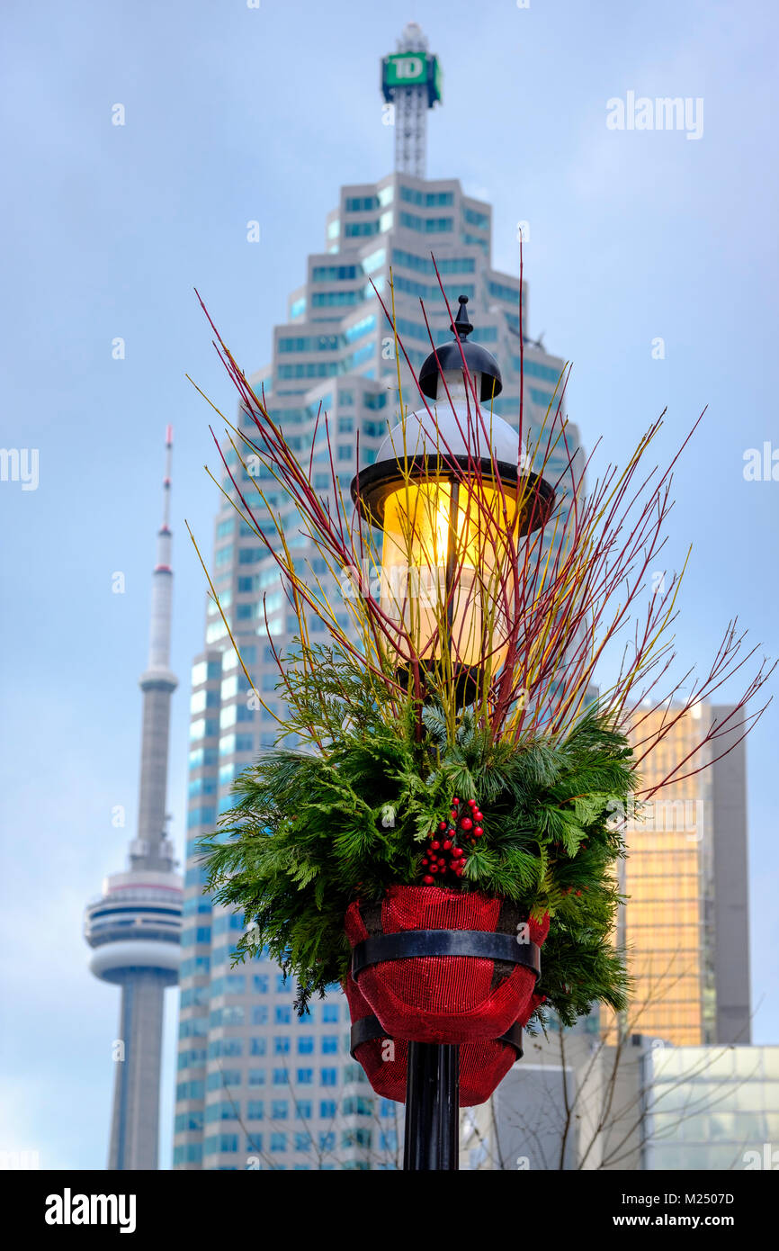 Strada illuminata luminosa e decorata per la stagione delle vacanze come sfondo per la CN Tower e TD Canada Trust Tower nel centro di Toronto, Canada. Foto Stock