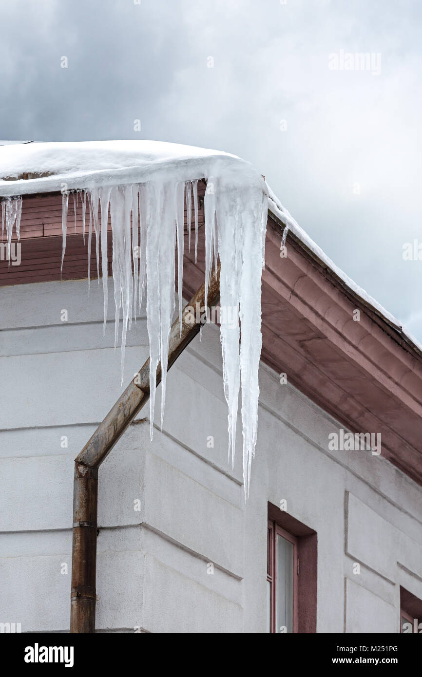 Il tetto del vecchio edificio della città ricoperta di neve e ghiaccioli a sbalzo Foto Stock